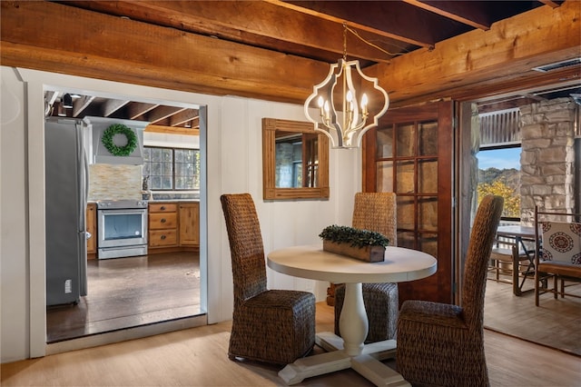 dining space with beam ceiling, light wood-type flooring, and an inviting chandelier