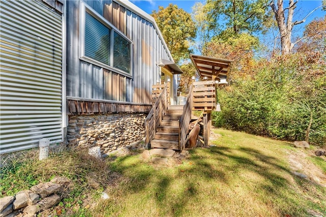 view of side of property featuring board and batten siding, a lawn, a gambrel roof, and stairs