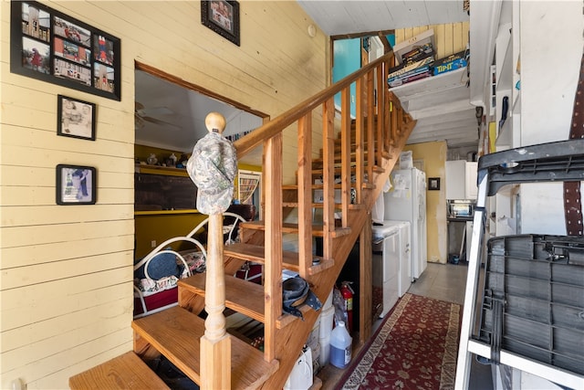 stairway featuring independent washer and dryer and wood walls