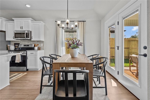 dining room with an inviting chandelier, plenty of natural light, and light wood-type flooring