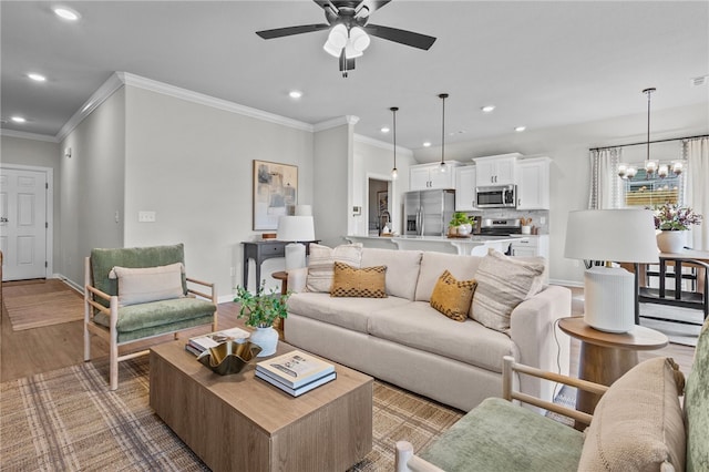 living room featuring crown molding, hardwood / wood-style flooring, and ceiling fan with notable chandelier