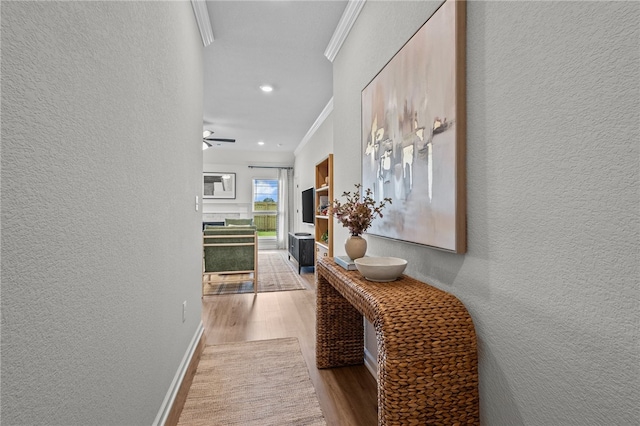 corridor with light hardwood / wood-style floors and crown molding