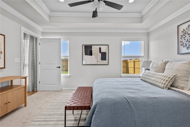 carpeted bedroom with ceiling fan, ornamental molding, and a tray ceiling