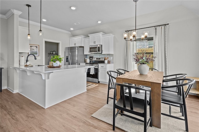 kitchen featuring appliances with stainless steel finishes, white cabinets, sink, and hanging light fixtures