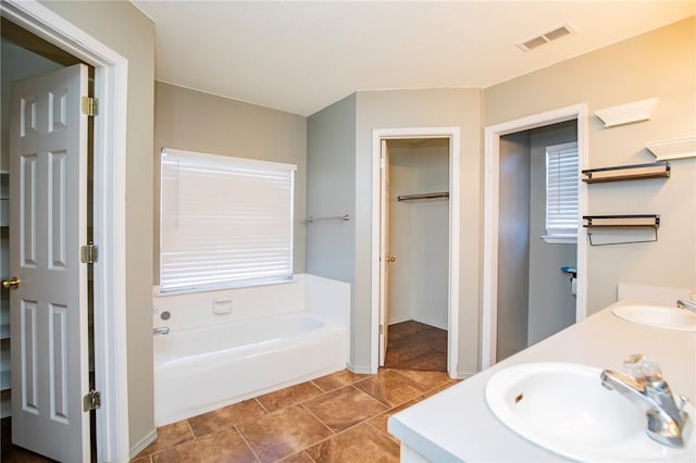 bathroom with tile patterned flooring, vanity, and a tub