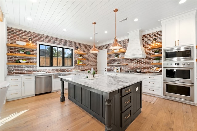 kitchen with stainless steel appliances, brick wall, and white cabinets