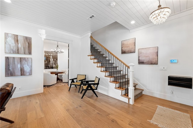 stairs featuring ornamental molding, hardwood / wood-style floors, wood ceiling, and an inviting chandelier