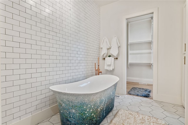 bathroom featuring a washtub, tile patterned floors, and tile walls