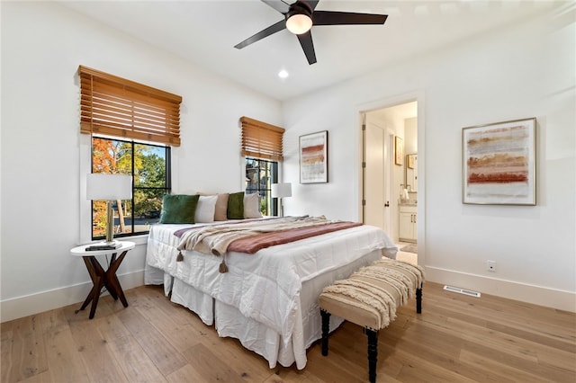 bedroom with light hardwood / wood-style flooring, ceiling fan, and ensuite bath