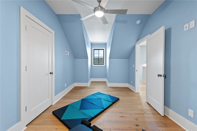 workout room featuring ceiling fan, lofted ceiling, and light hardwood / wood-style flooring