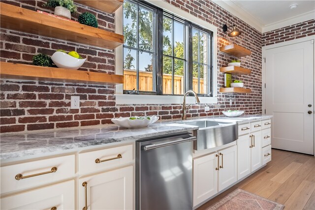 kitchen featuring light stone counters, brick wall, dishwasher, and sink