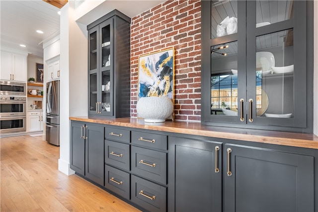 kitchen featuring stainless steel appliances, white cabinetry, wooden counters, and light hardwood / wood-style floors