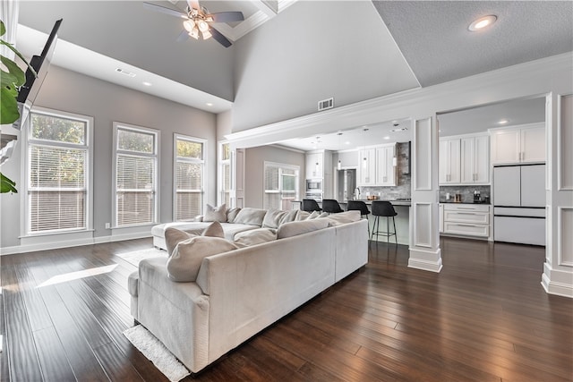 living room with crown molding, dark hardwood / wood-style floors, high vaulted ceiling, and ceiling fan