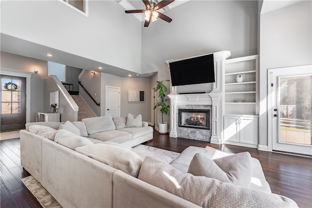 living room with a multi sided fireplace, dark hardwood / wood-style floors, a high ceiling, and ceiling fan