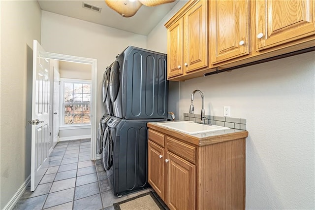 washroom with cabinets, ceiling fan, light tile patterned floors, sink, and stacked washer and clothes dryer