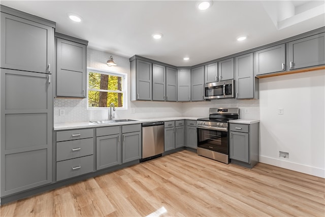 kitchen featuring light wood-type flooring, stainless steel appliances, sink, and gray cabinetry