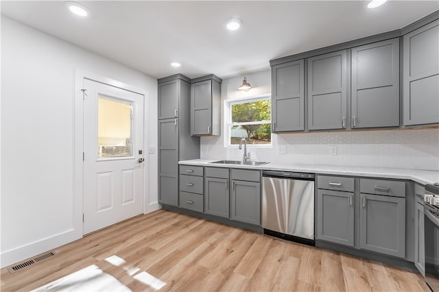 kitchen with gray cabinets, stainless steel appliances, sink, and light wood-type flooring