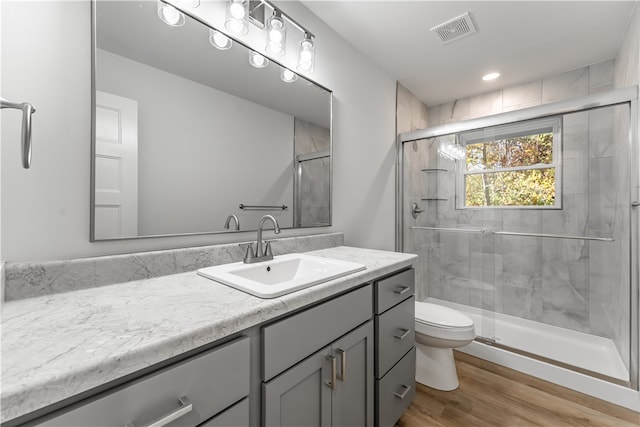 bathroom with toilet, vanity, hardwood / wood-style floors, and a shower with shower door