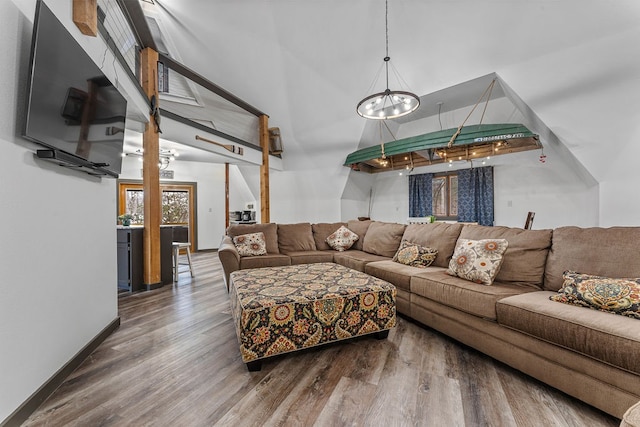 living room featuring beamed ceiling, a chandelier, wood-type flooring, and a high ceiling