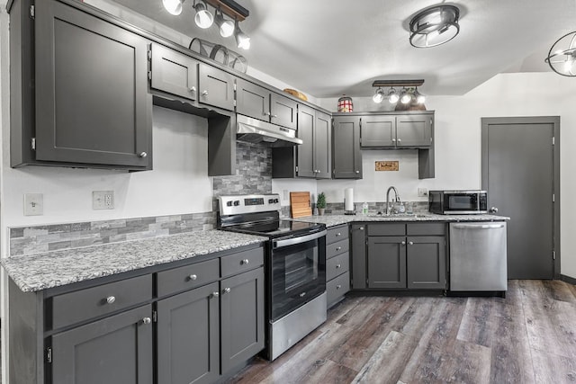 kitchen featuring dark wood-type flooring, gray cabinetry, stainless steel appliances, sink, and light stone counters