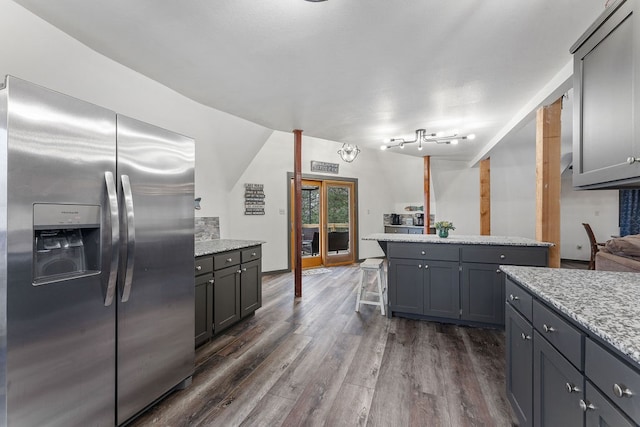 kitchen with gray cabinets, dark wood-type flooring, stainless steel fridge with ice dispenser, and light stone counters