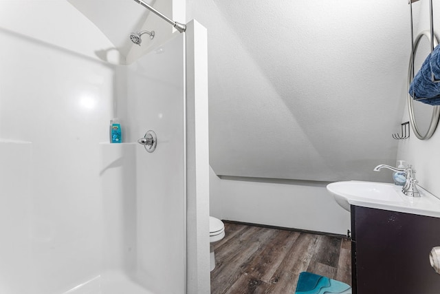 bathroom featuring lofted ceiling, hardwood / wood-style floors, a shower, toilet, and vanity