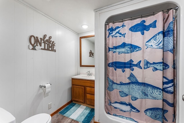 bathroom with toilet, a shower with curtain, hardwood / wood-style floors, vanity, and wood walls