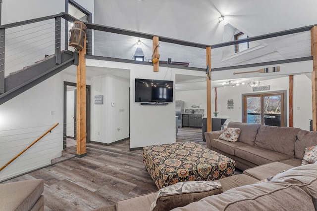 living room with an inviting chandelier, hardwood / wood-style flooring, and high vaulted ceiling