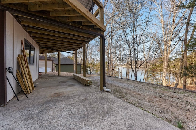 view of patio / terrace featuring an outbuilding, a garage, and a water view