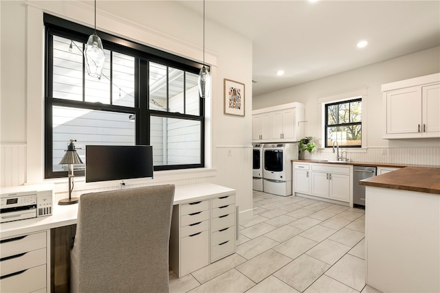 kitchen featuring independent washer and dryer, butcher block countertops, decorative light fixtures, stainless steel dishwasher, and white cabinets