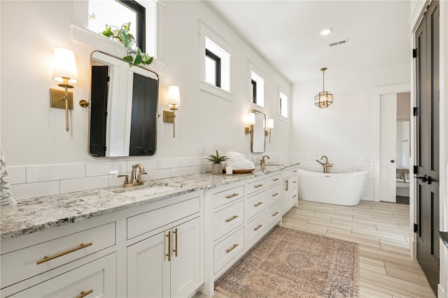 bathroom with vanity, tile walls, wood-type flooring, and a bathing tub