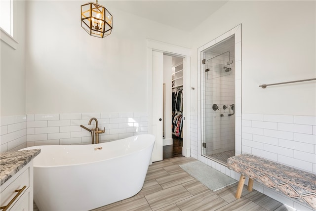 bathroom featuring vanity, tile walls, and separate shower and tub