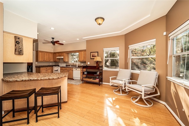 kitchen featuring kitchen peninsula, white appliances, ceiling fan, sink, and light hardwood / wood-style floors