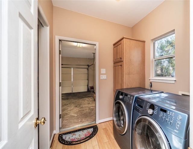 laundry room with cabinets, washer and clothes dryer, and light hardwood / wood-style floors