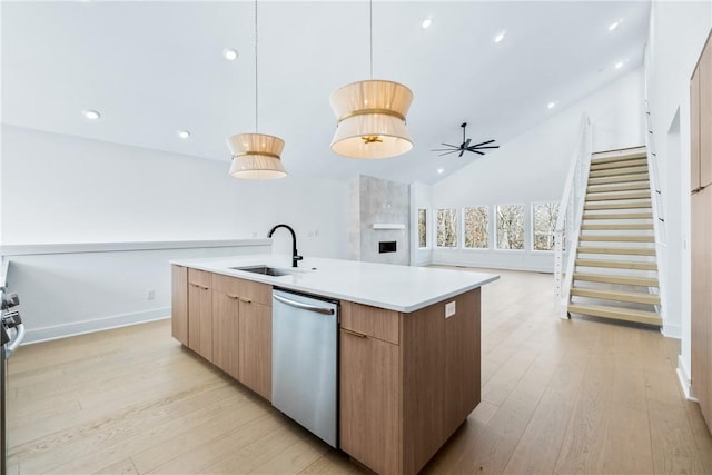 kitchen featuring a center island with sink, light hardwood / wood-style flooring, sink, appliances with stainless steel finishes, and pendant lighting