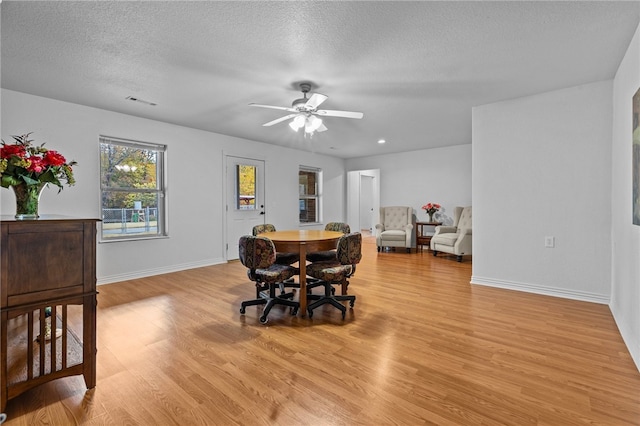 dining area with light hardwood / wood-style flooring, a textured ceiling, and ceiling fan