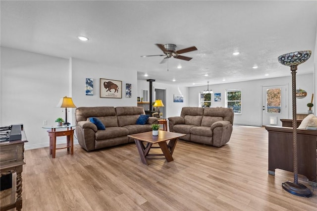 9299 W Forest Hills Dr, Fayetteville, AR 72704 - living area with light wood-type flooring, recessed lighting, a wood stove, a ceiling fan, and baseboards