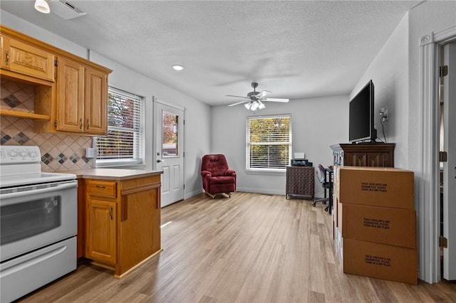 9299 W Forest Hills Dr, Fayetteville, AR 72704 - kitchen with white electric range, light wood-style floors, light countertops, backsplash, and plenty of natural light