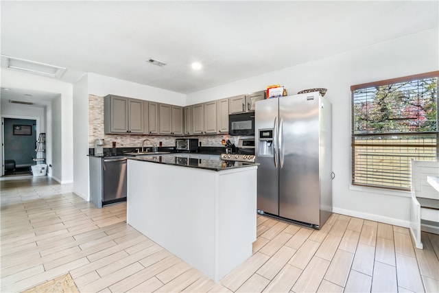 kitchen with a kitchen island, appliances with stainless steel finishes, light hardwood / wood-style floors, and tasteful backsplash