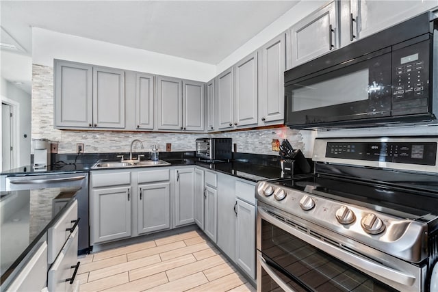 kitchen with tasteful backsplash, stainless steel stove, gray cabinetry, light hardwood / wood-style floors, and sink