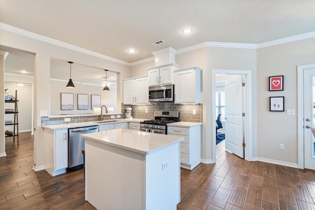 kitchen featuring appliances with stainless steel finishes, pendant lighting, white cabinetry, sink, and a center island