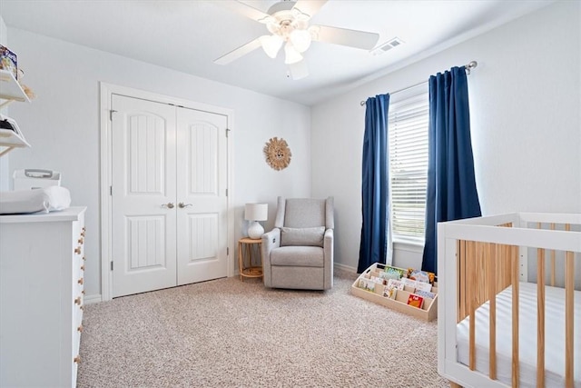 carpeted bedroom featuring a crib, a closet, and ceiling fan