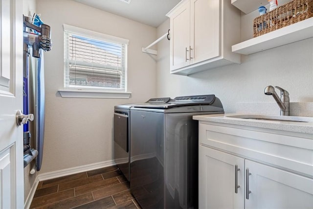 clothes washing area with cabinets, sink, and washer and clothes dryer