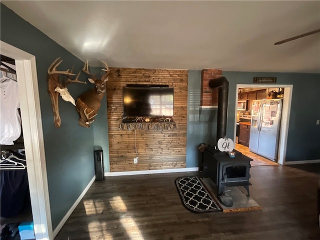 unfurnished living room featuring hardwood / wood-style flooring, a wood stove, and wood walls