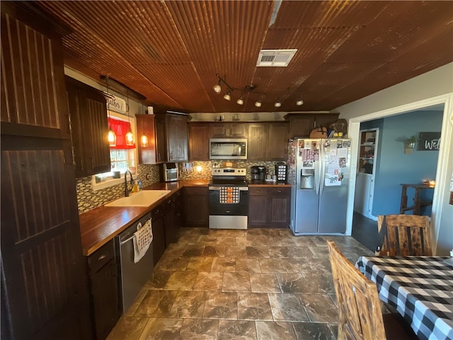 kitchen with sink, stainless steel appliances, dark brown cabinetry, pendant lighting, and decorative backsplash