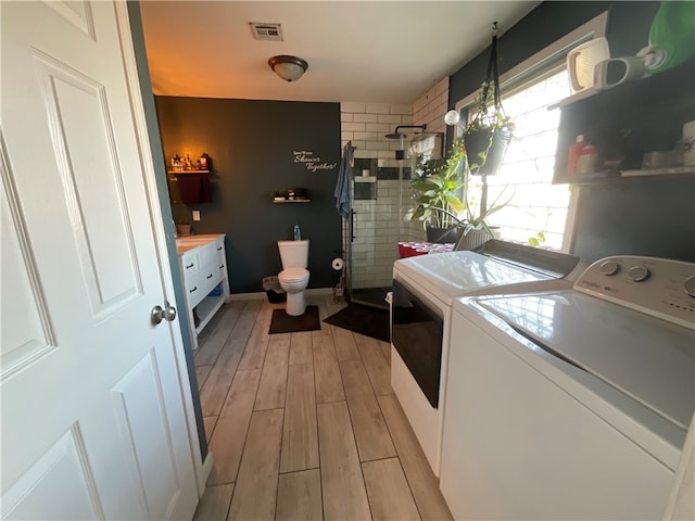 clothes washing area featuring independent washer and dryer, a healthy amount of sunlight, and light hardwood / wood-style floors