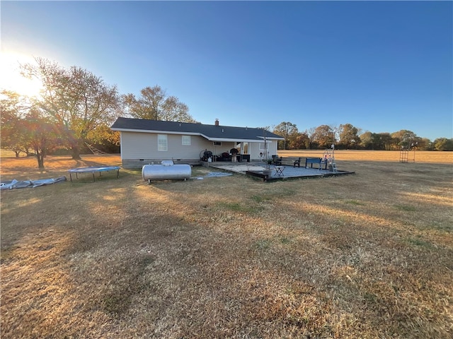 rear view of property featuring a yard, a trampoline, and a patio