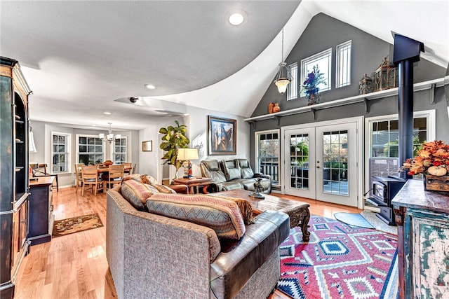 living room featuring french doors, an inviting chandelier, light hardwood / wood-style flooring, high vaulted ceiling, and a textured ceiling