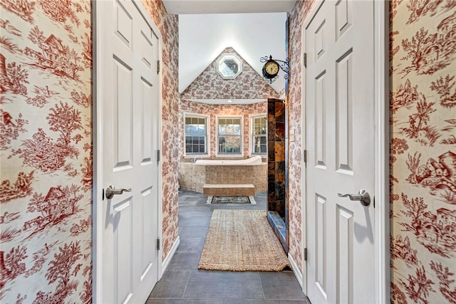 bathroom featuring a bath, vaulted ceiling, and tile patterned floors