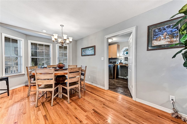 dining space with light hardwood / wood-style floors and an inviting chandelier